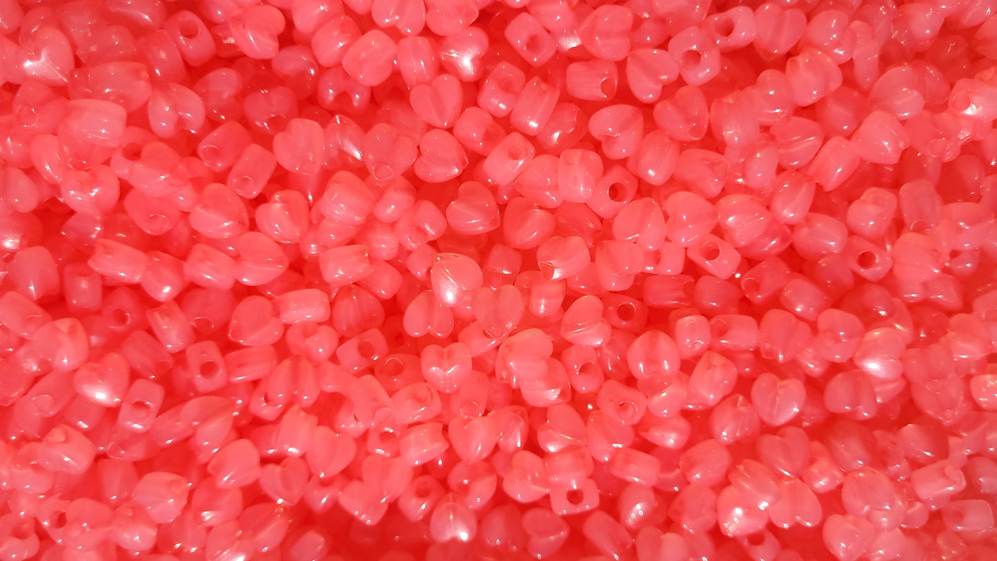 Close-up of pink heart-shaped beads on a red background